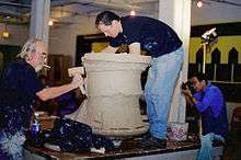 Two men making a large ceramic sculpture