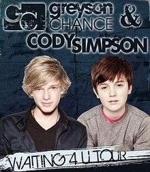 Image of two teen boys side by side. A blonde boys sits on the left of the image wearing a black shirt with a navy blue jacket. A brunet boy sits on the right of the image wearing a red shirt with a beige sweater. On top of the two boys, the word "greyson CHANCE & CODY SIMPSON" are written in blue with a white glow behind the font. Below the two teen boys, the word "WAITING 4U TOUR" are written in blue.