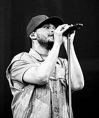 A Black and white photo of a man singing with a microphone stand in front of him