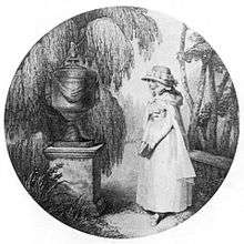 A young girl standing in front of an urn and surrounded by ferns.