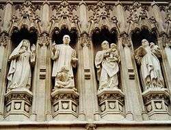 Photo shows four of ten statues above the door of the Abbey. They are carved in a realistic and lifelike manner, full of action. Elizabeth wears nun's habit and holds a cross, King preaches with a little black girl at his feet, Romero holds a naked indigenous baby, Bonhoeffer carries a book. They are set in traditional Gothic niches with ornate carved canopies.
