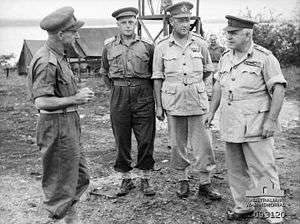 Four men in uniforms without ties, but wearing peaked caps.