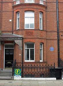 A semi-detached red-brick Georgian house, with a small blue plague on the wall.