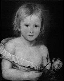 Black-and-white half-length portrait of a toddler, wearing a small shirt that is falling off of his body, revealing half of his chest. He has short blonde hair and is holding a rose.