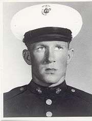 A black and white image of Wilson wearing his Marine Corps dress blue uniform with White dress hat.