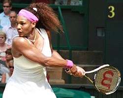 A black woman wearing a white ensemble with purple accents and headband