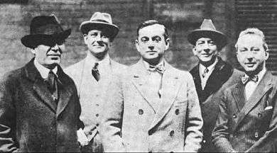 black and white photograph of five well-dressed men standing facing the camera