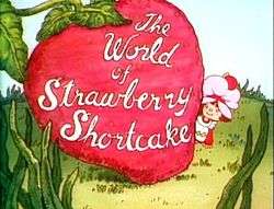 A six-year-old girl, dressed in a pinafore and wearing a pink dust cap on top of her hair, looks out to the right of a giant strawberry.  On the strawberry, the words "The World of Strawberry Shortcake" are written in cursive.