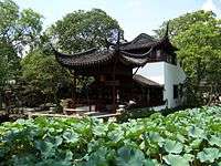 Chinese style pavilion near a pond with lotuses.