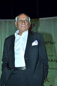 Yash Chopra is standing with his hands in his pockets, and looking away from the camera