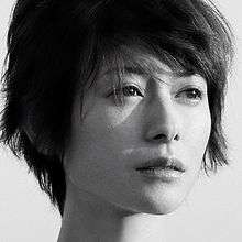 The face of a woman with short hair in greyscale. She is looking to her left towards sunlight.