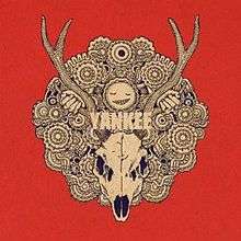 A black and white drawing of a deer's skull with large antlers on a red background, in the middle of a round pattern with many patterned circles. Above the skull is a smiling face, with two hands holding onto its antlers. In the middle of the pattern are the letters "YANKEE" written in white.
