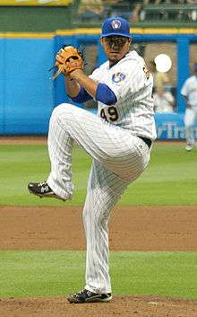 An action photograph of a baseball player pitching a baseball.