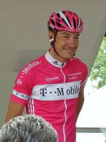 A cyclist wearing a pink jersey and a helmet.