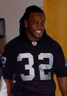 Candid photograph of Crockett smiling an wearing an Oakland Raiders #32 jersey