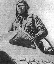 A Chinese man in a flight suit standing in the cockpit of an aircraft.