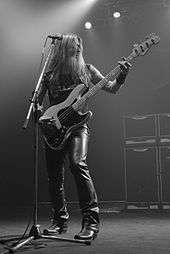 A long-haired man playing bass guitar onstage